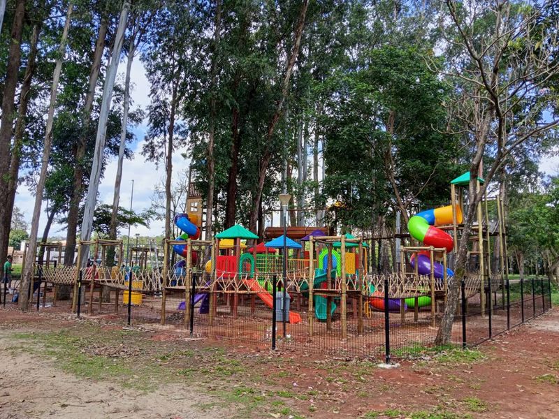 Kidsplay com telhadinhos coloridos, escorregadores e tubos espirais, cercado por grade preta